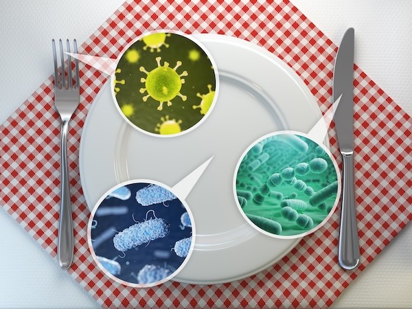 A white dinner plate is set on a red and white checkered napkin with a fork on the left and a knife on the right. The plate features magnified close-up images of various bacteria and viruses, highlighted in circular frames.